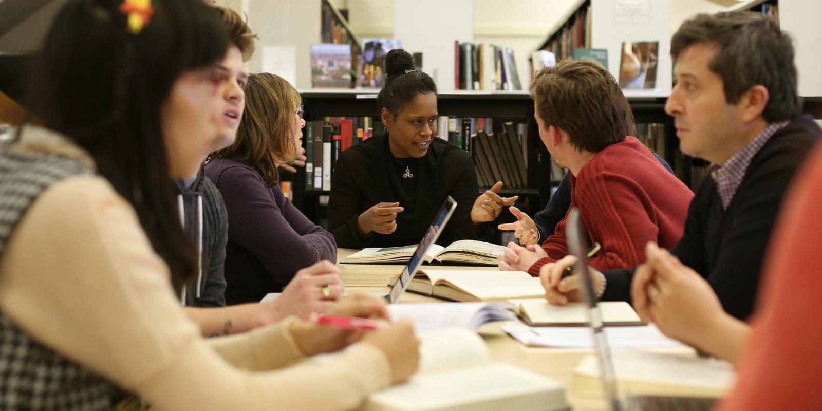 Professor in the middle of the table talking to students