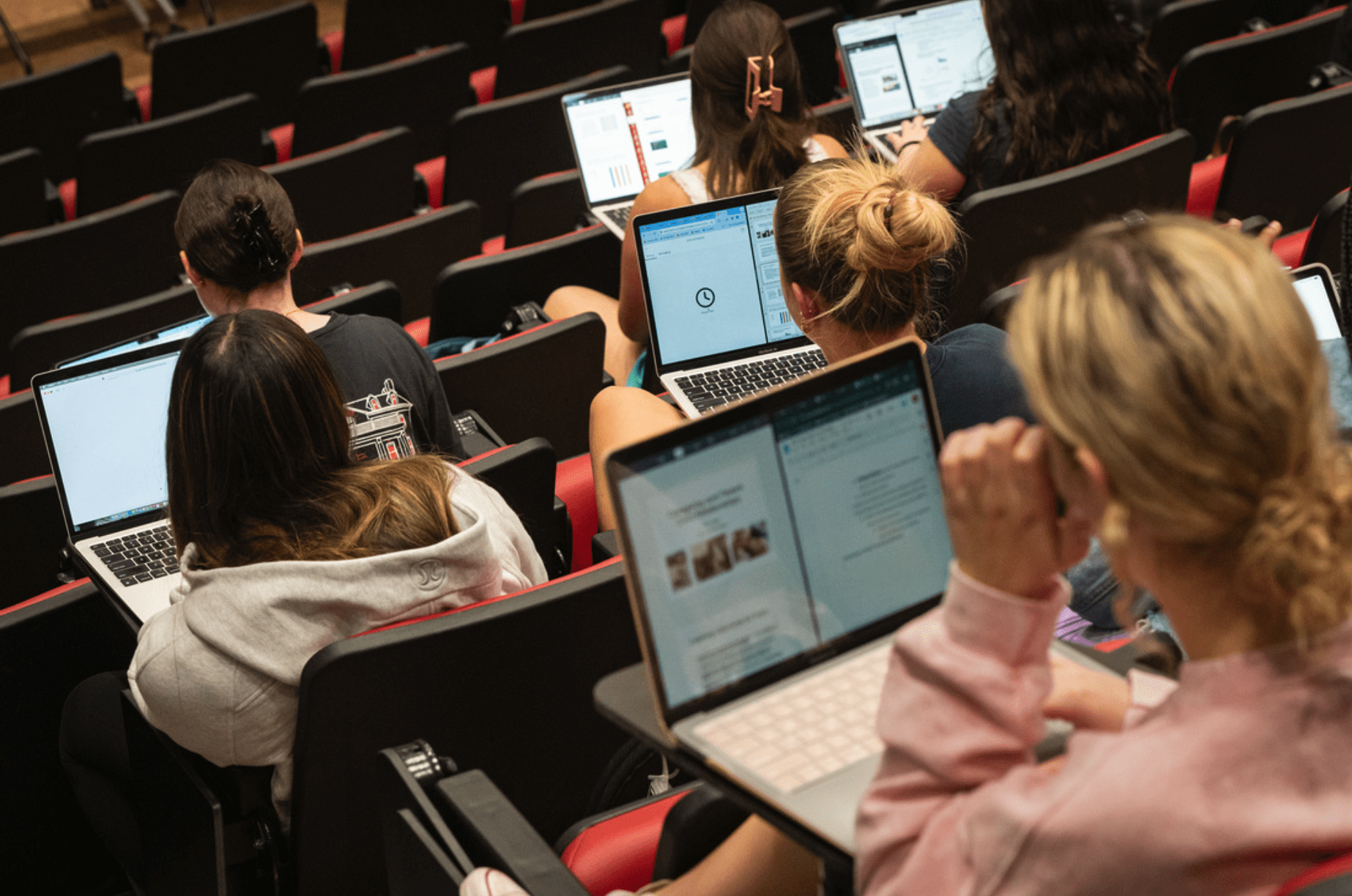 Students with open laptops in an auditorium