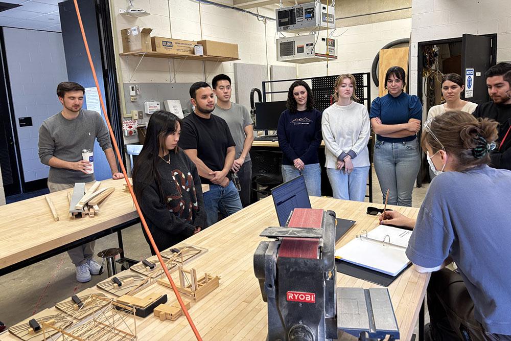 Students gathering around a wood shop table