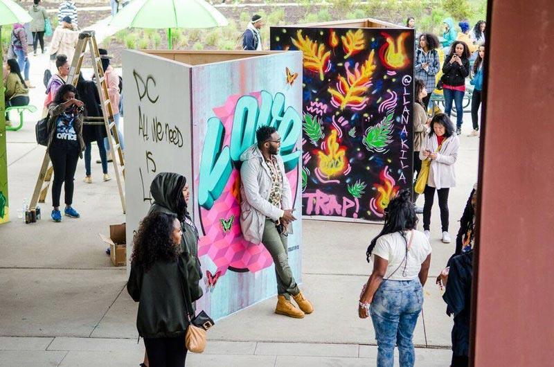 Visitors standing in the festival gateway with colorful spray painted walls