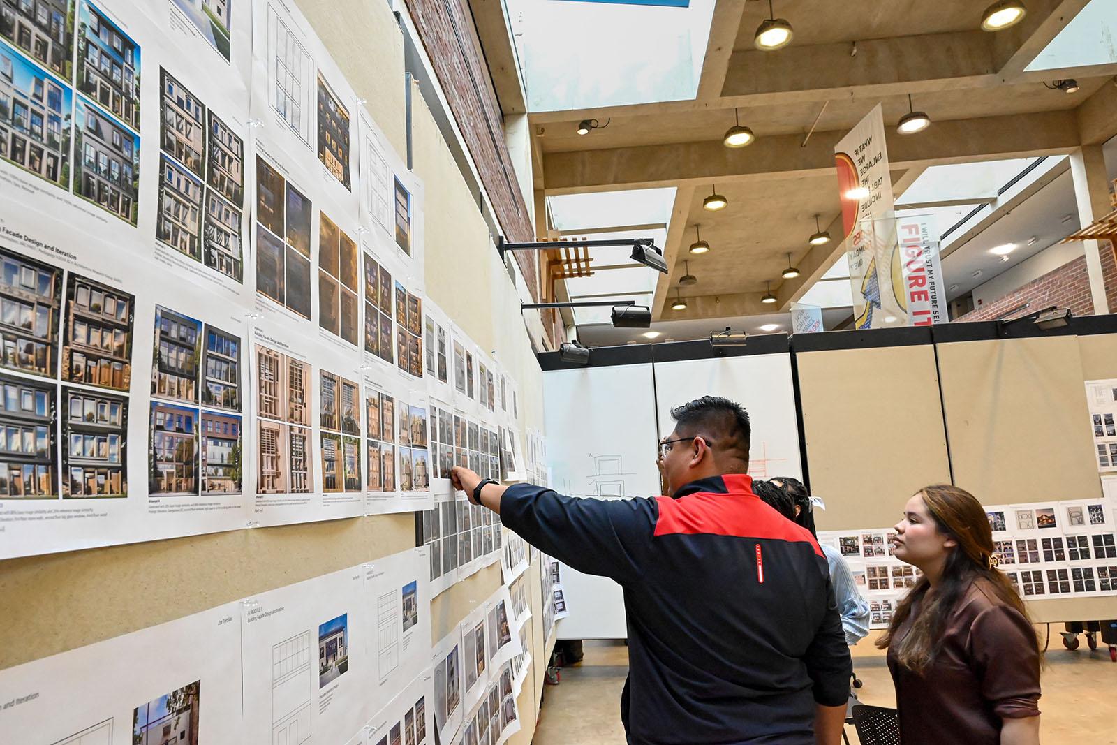 Students pointing to pinned up work in the Great Space