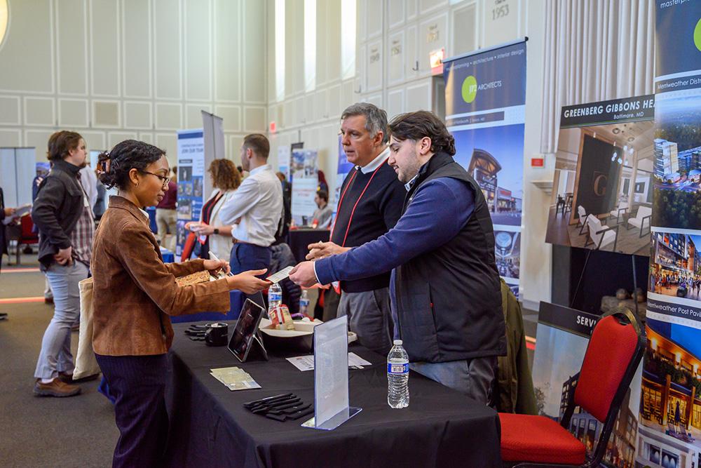 Man handing a business card to a Career fair attendee