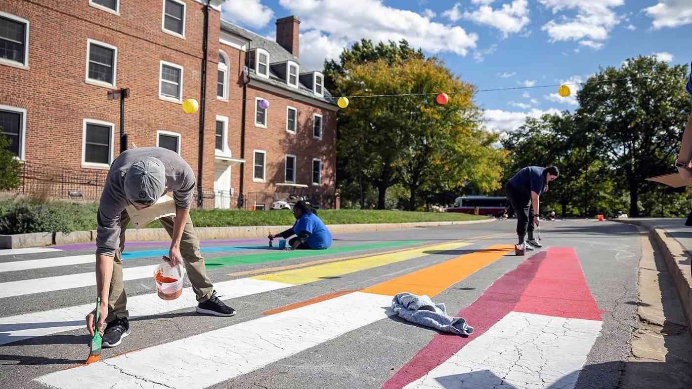 People painting crosswalk signage in various colors