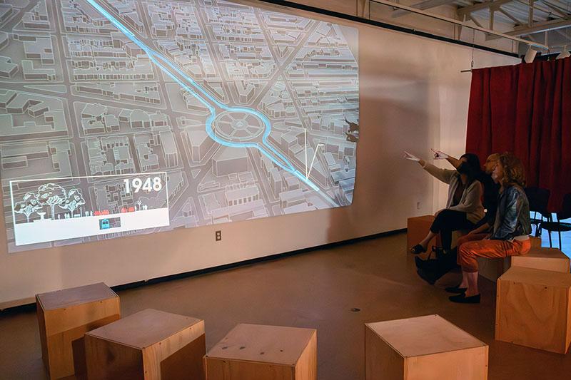 People sitting on wooden cubes and pointing to a screen of the Dupont Underground sitemap