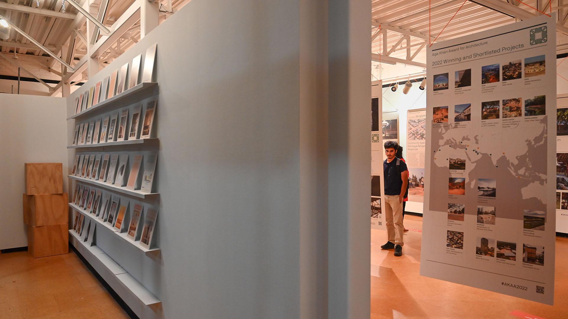 In the foreground are bookshelves and in the back is a person looking at the exhibit