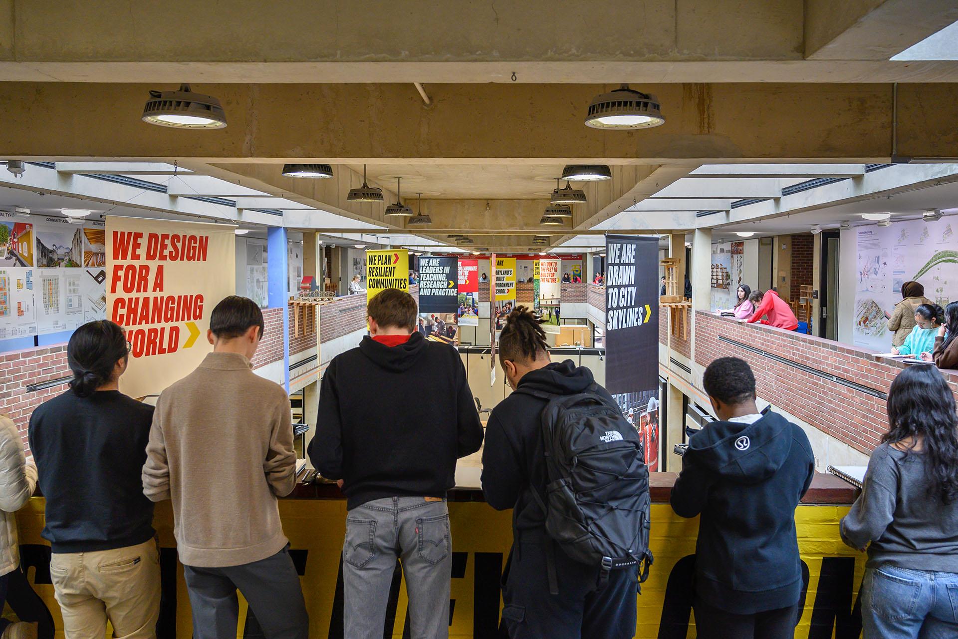 Students sketching in the Mezzanine, banners are hanging saying from the Great Space in front of them