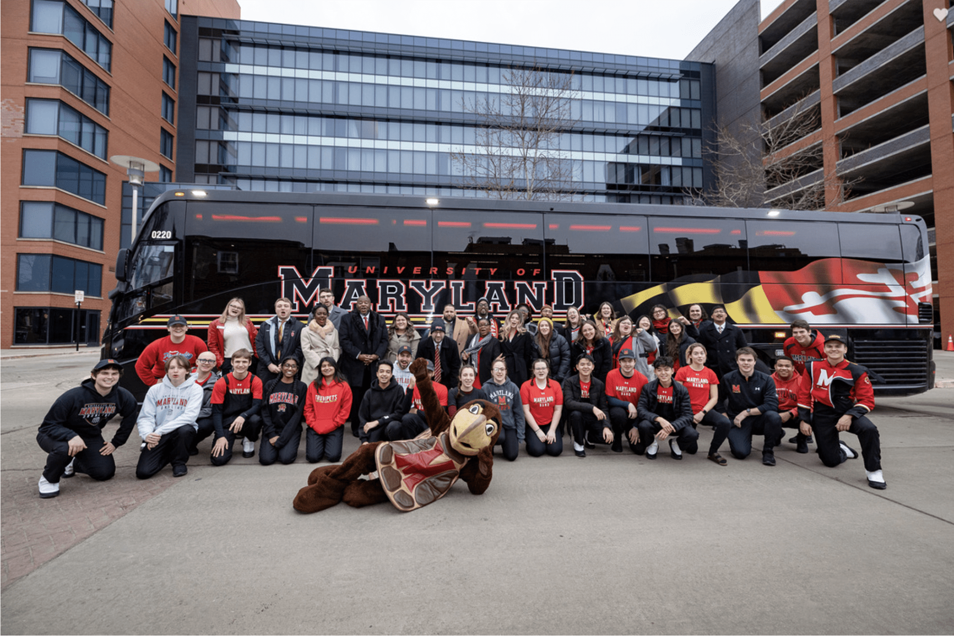 Group photo of admitted students with Testudo in front of a Maryladn bus