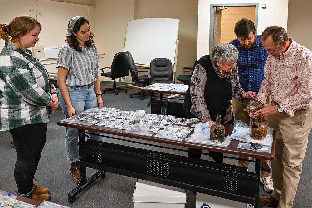 Students and professors looking at artifacts.