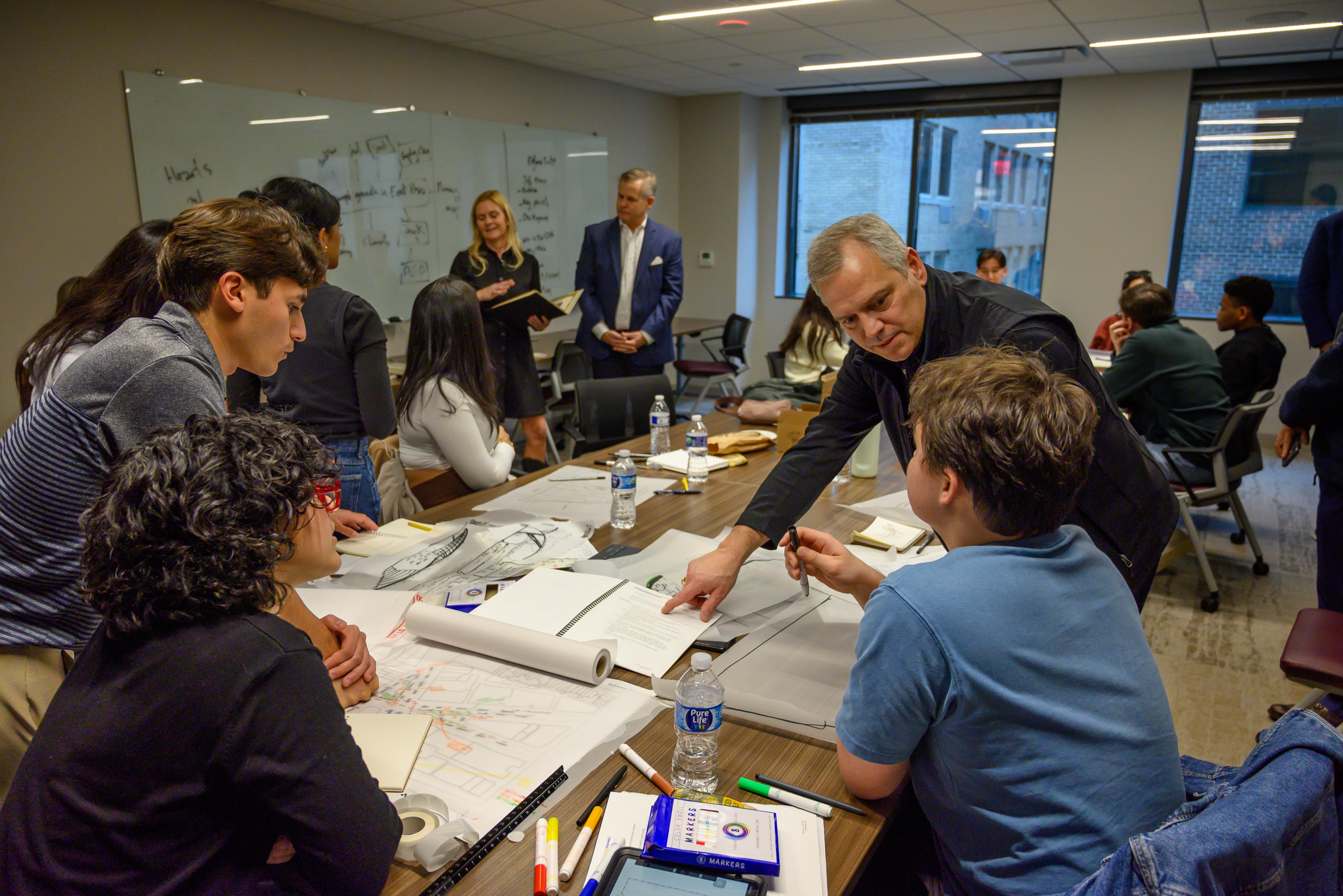 Professor advising students on their architectural charrette drawings