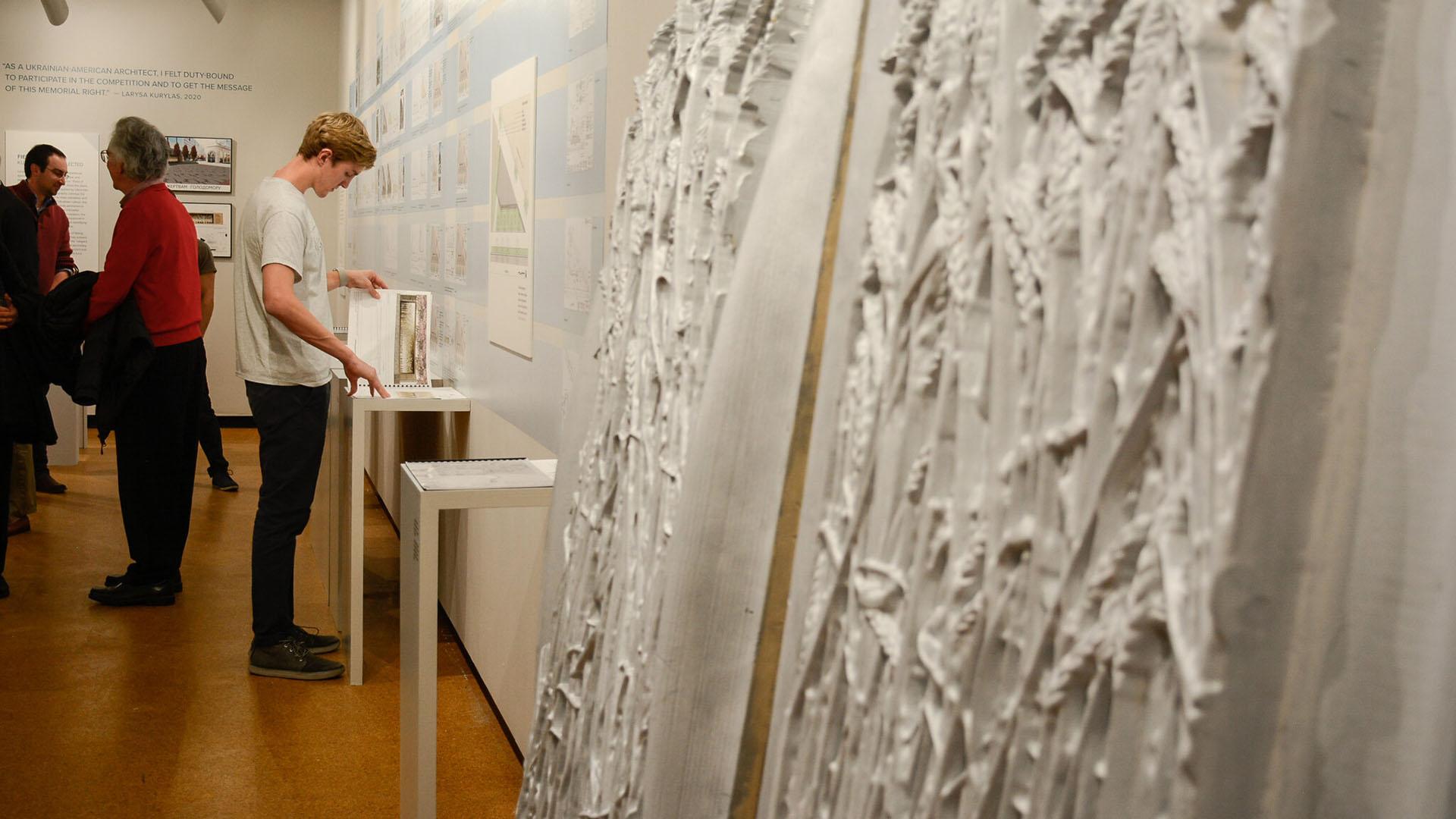 A person reading a book with holodomor memorial molds in the foreground