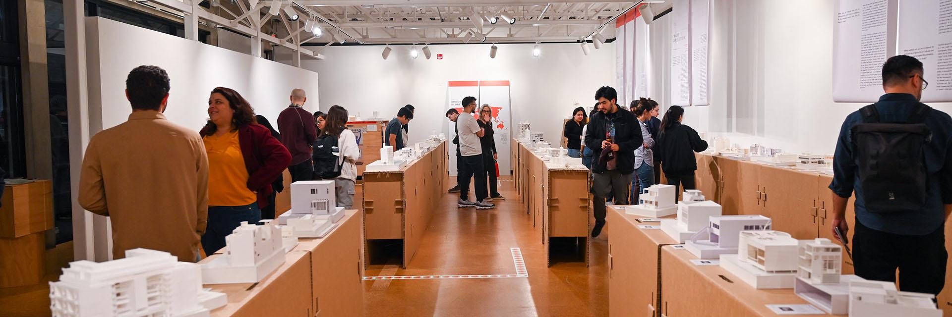 People at a Kibel gallery opening, surrounded by many white architectural models