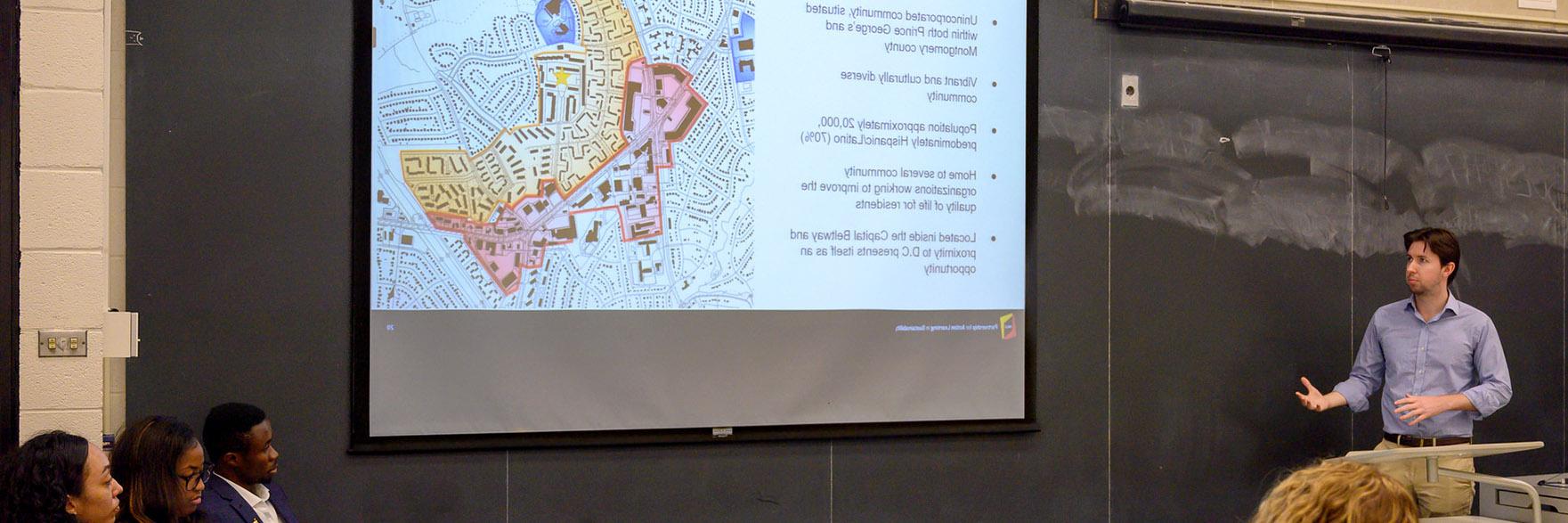Student presenting a plan analysis projected on screen