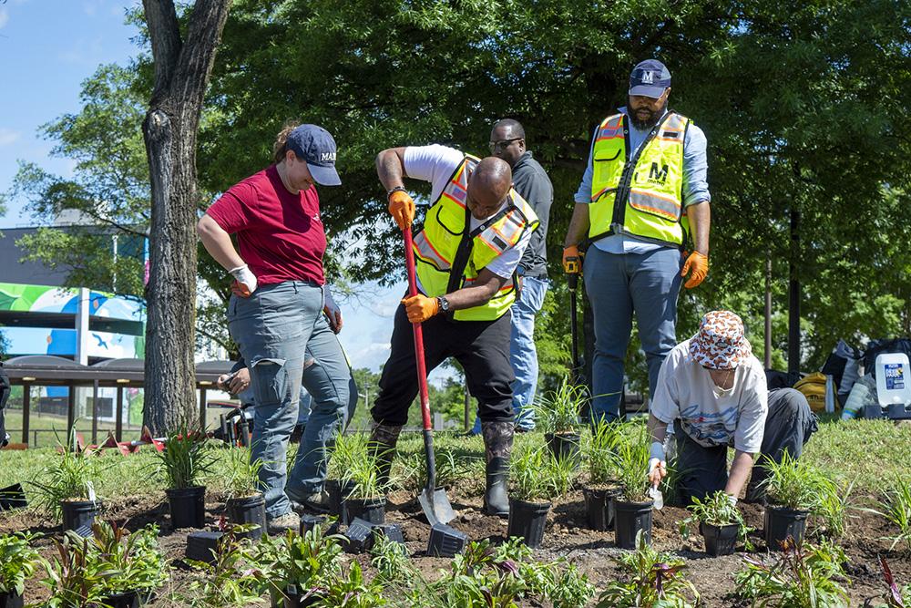 A group of people planting plants wearing safety vests. 