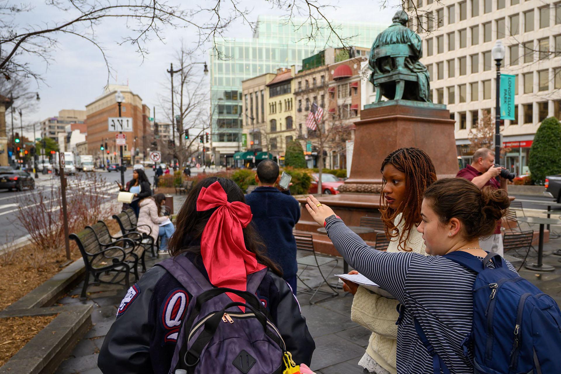 Students pointing and sketching towards in downtown Washington DC. A statue and buildings are in the background