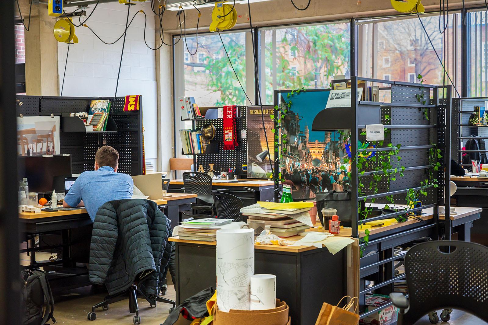 Decorated studio spaces with foliage and posters. A student works in the background