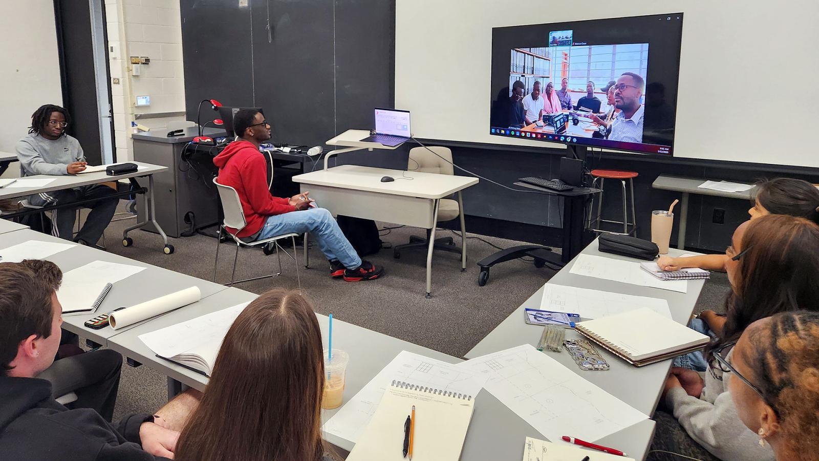 People in a classroom on a Zoom call with students for Uganda Martyrs University