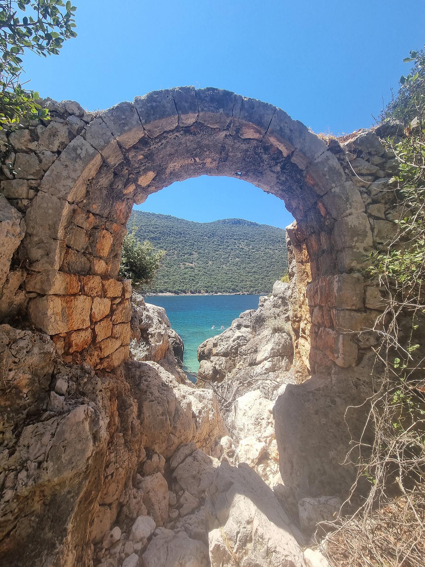 An ancient bridge in Aperlae Turkey with a blue ocean in the background.