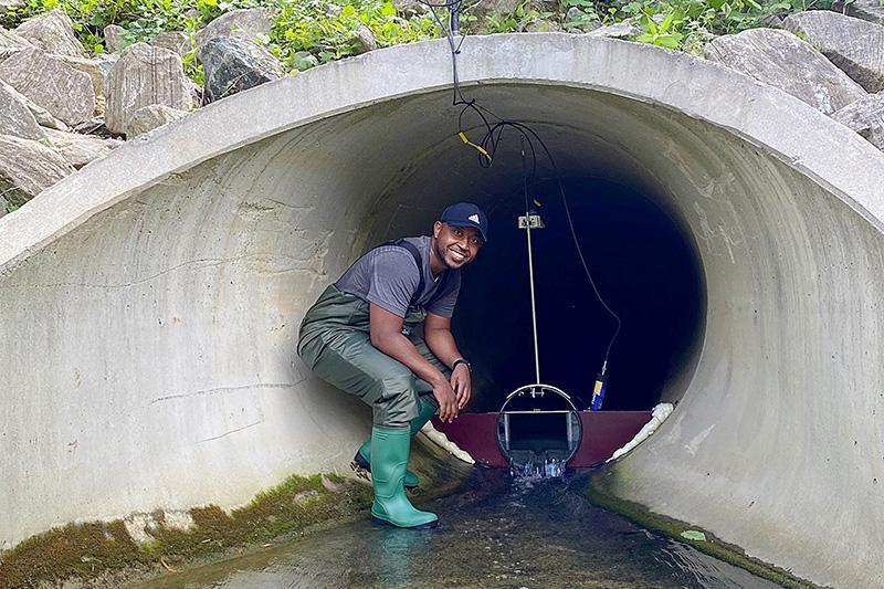 Man stands in stormwater entrance with research machinery