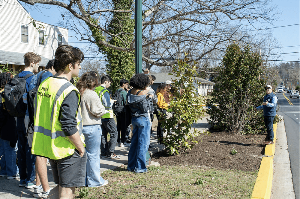 SIRJ lab members in the community, by the street, a man is speaking to them