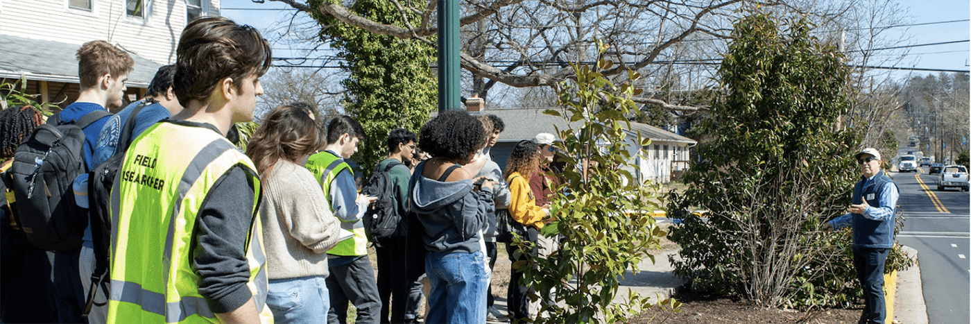 SIRJ lab members in the community, by the street, a man is speaking to them