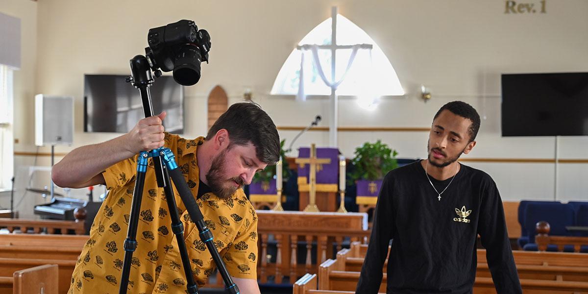 Stephan holding a camera a student by him in the Zion Church