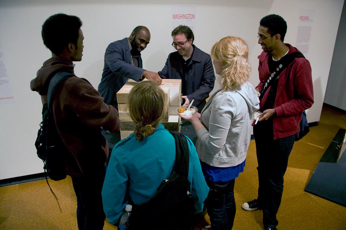 People looking at an exhibit's dresser trunk