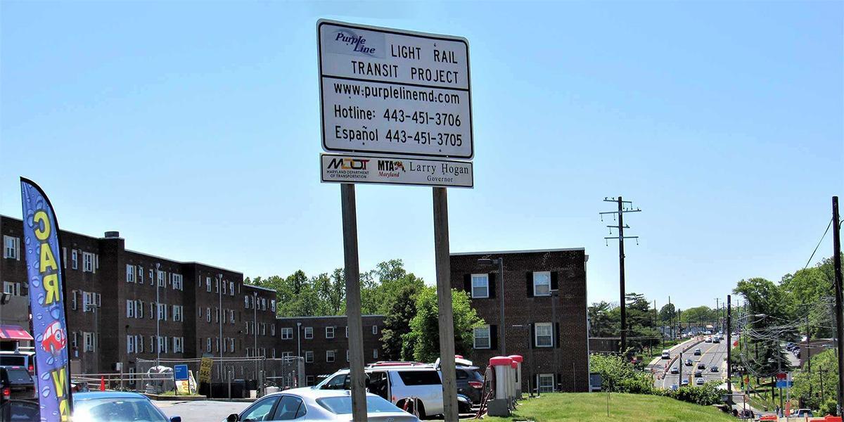A sign for the Purple Line Rail with buildings in the background