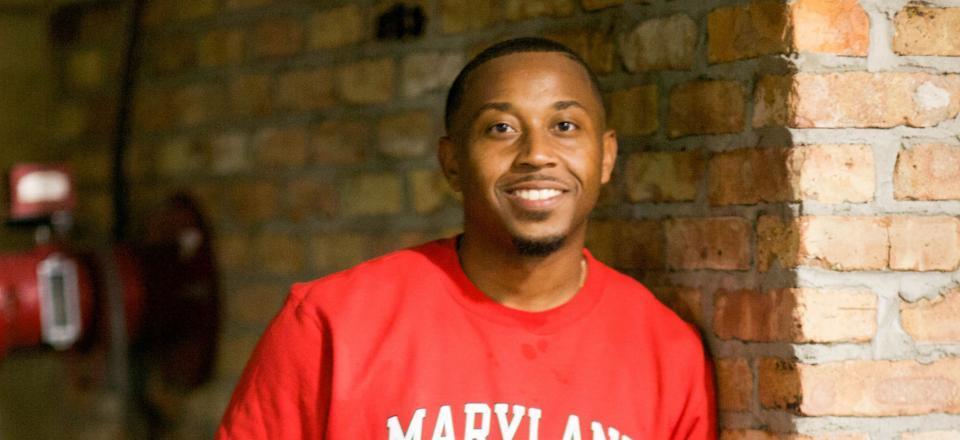 An African American man in a red shirt smiling for a photo. 