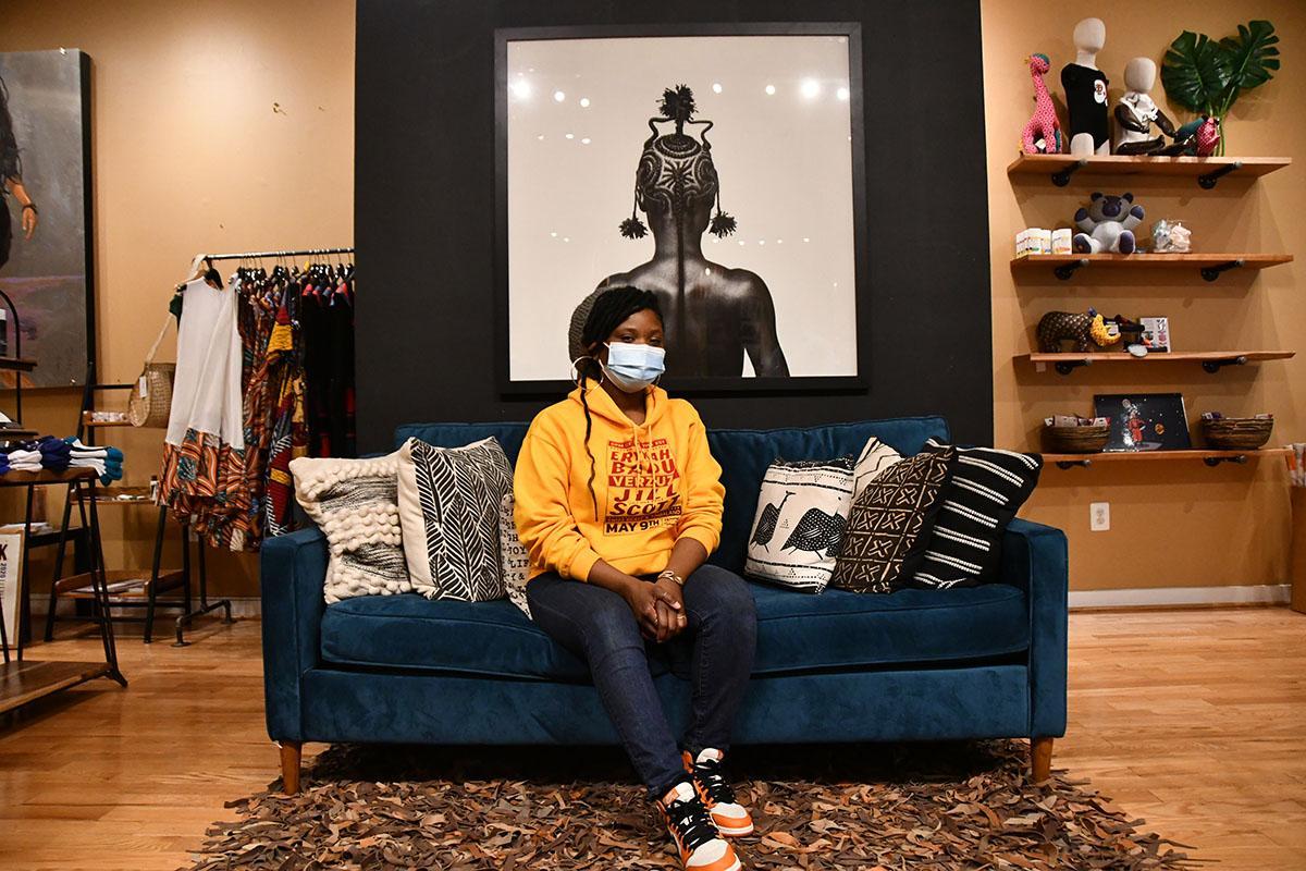 A women with a mask sitting on a blue couch. 