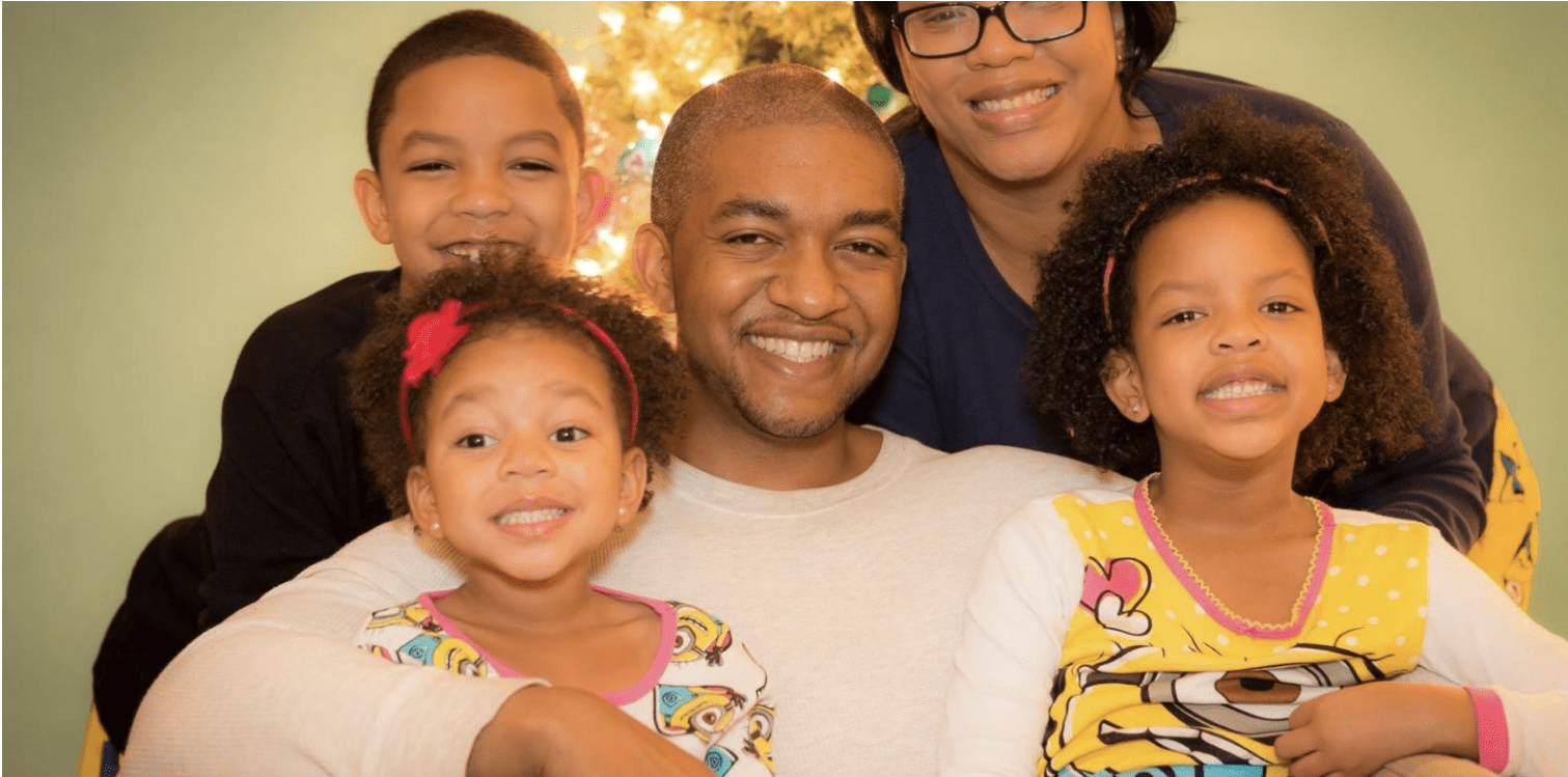 A family of five smiling for a photo. 