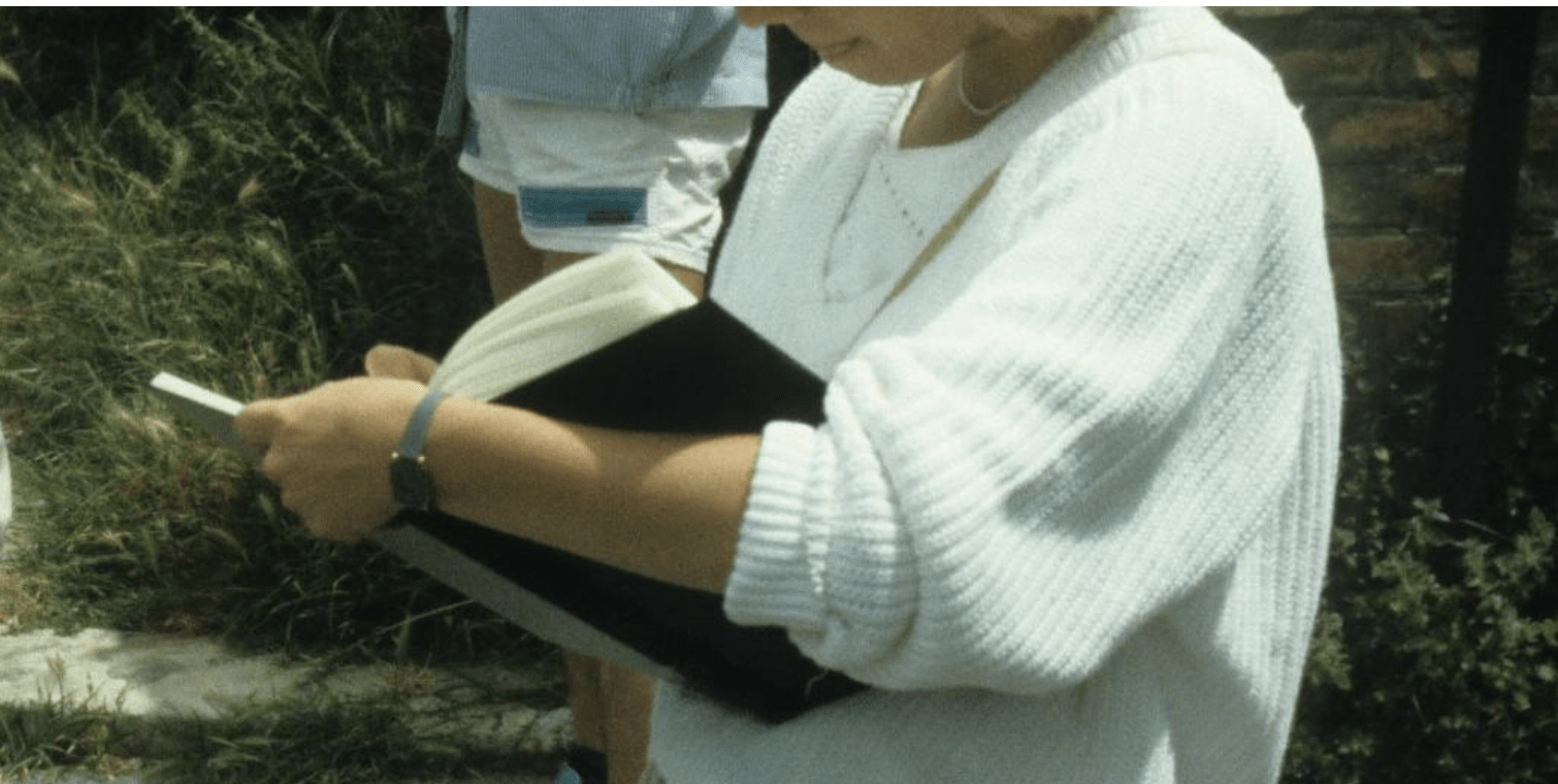 Photo of a woman, neck down, reading a book. 