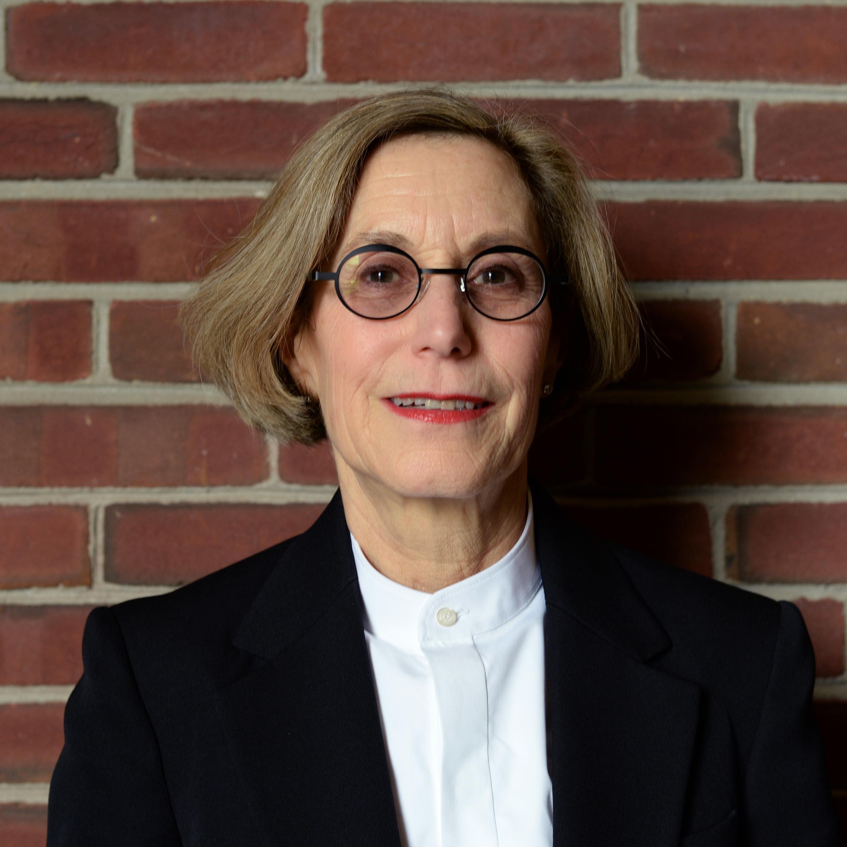 Older woman with glasses smiling for a professional headshot. 