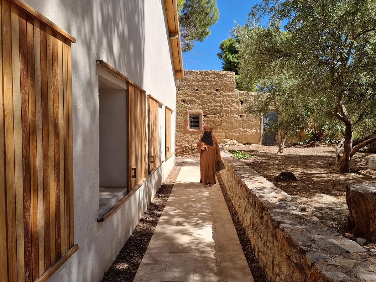 A woman dressed in a burka walking through Moroccan architecture.