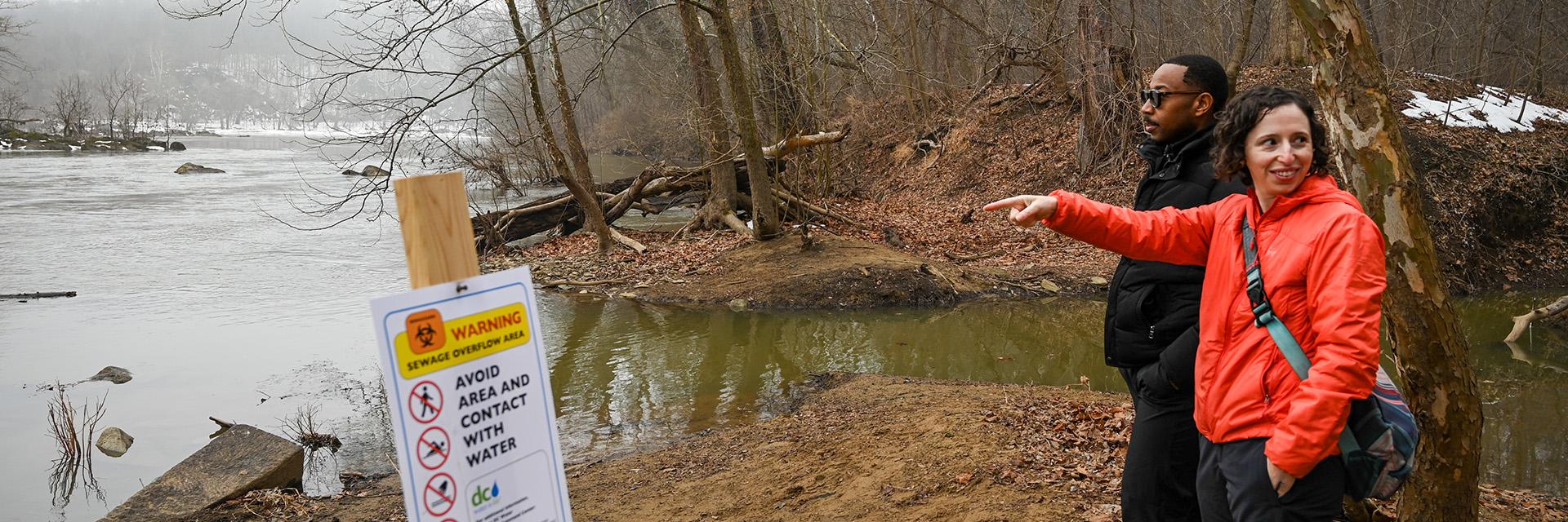 Rachel Goldstein pointing to the Potomac water spillage, Marccus Hendricks is next to her