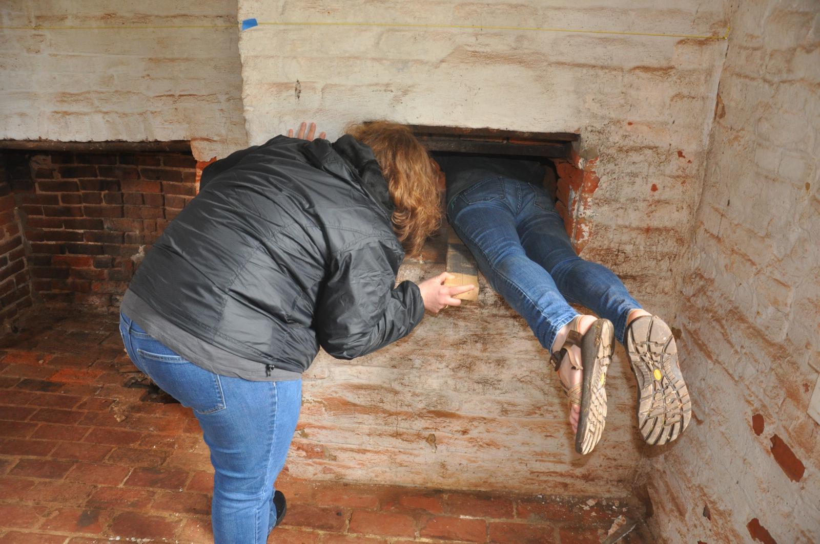 A women helping a man climb into a tunnel