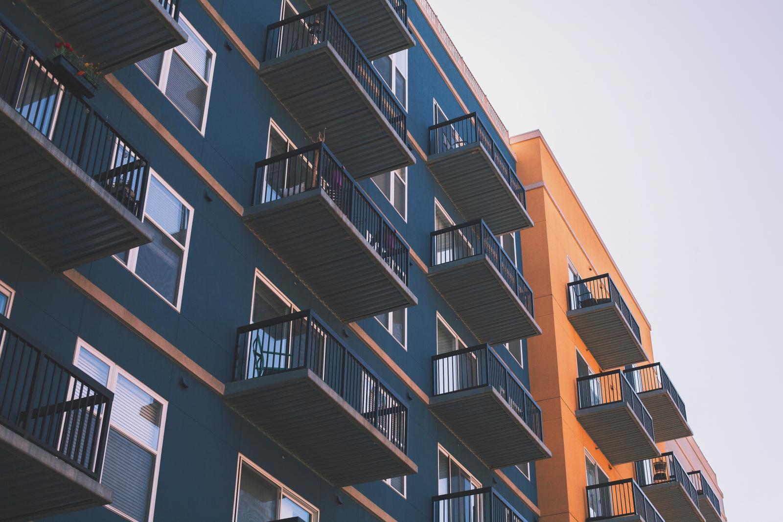Close up of one blue and one orange building with balconies 