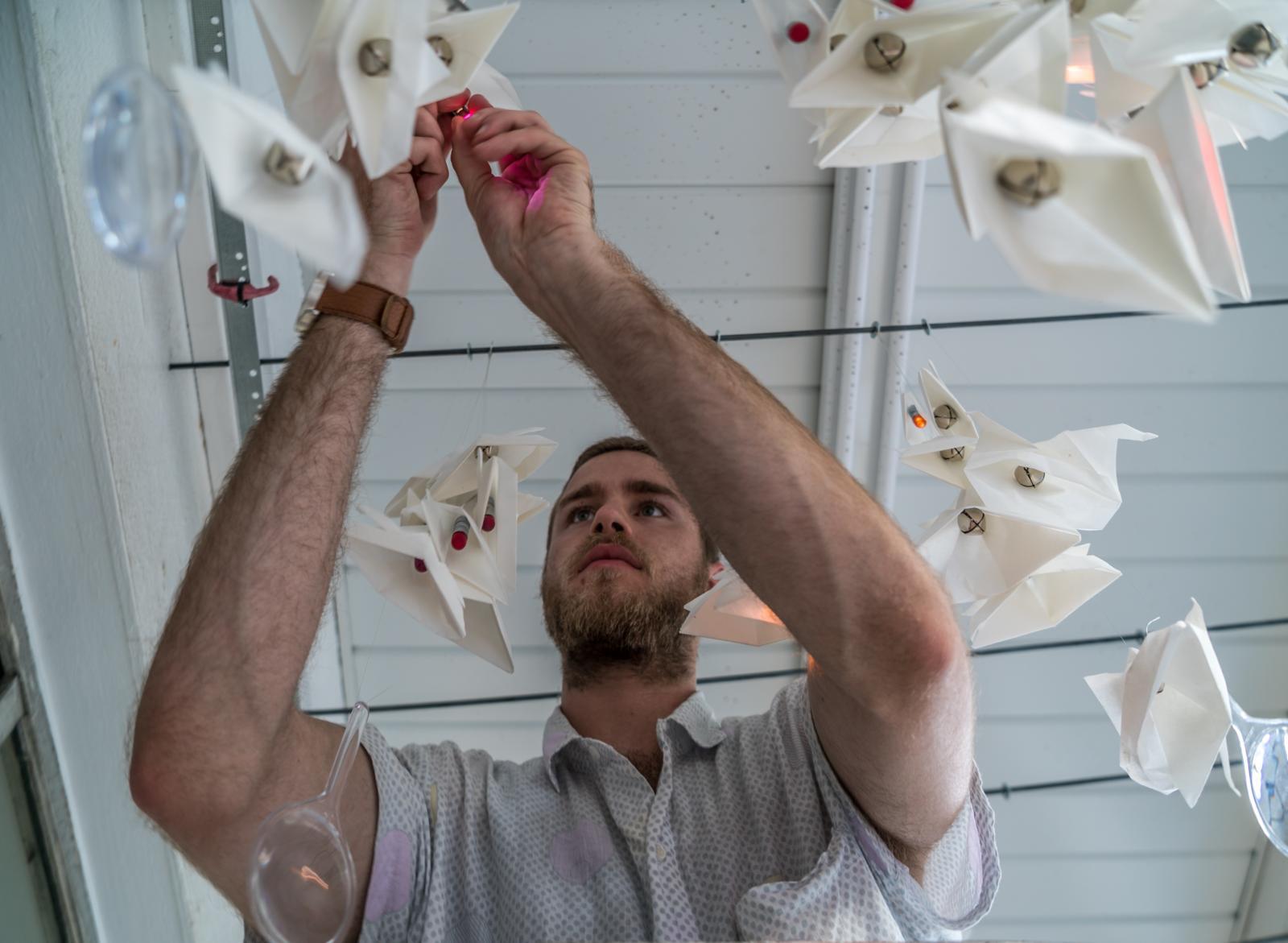 Male hanging artwork from the ceiling 