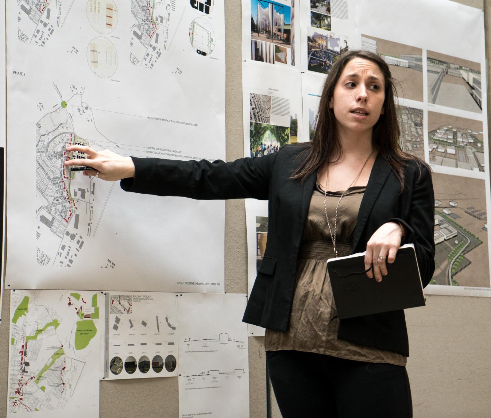 Lady pointing at architecture sketch on board 