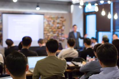 Business People Meeting and Working while Business Executive Lead Presenter Speaks to Group