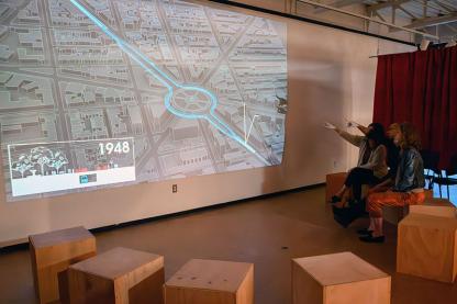 People sitting on wooden cubes and pointing to a screen of the Dupont Underground sitemap