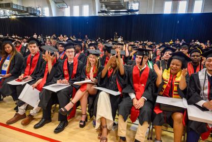 Students moving their tassels and clapping at commencement