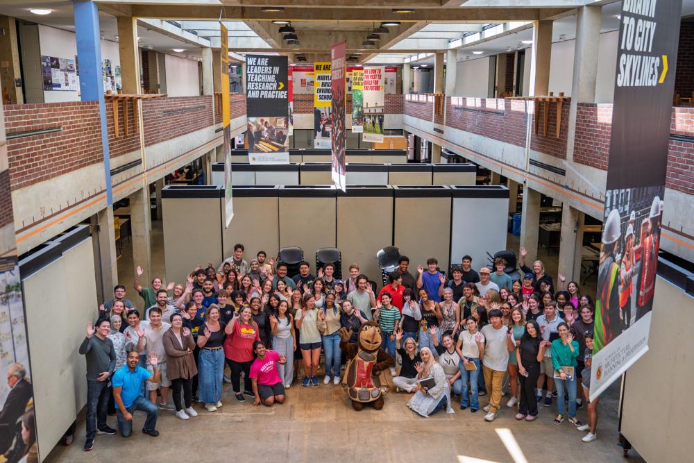 Group shot of students, faculty and staff in the Great Space with Testudo.